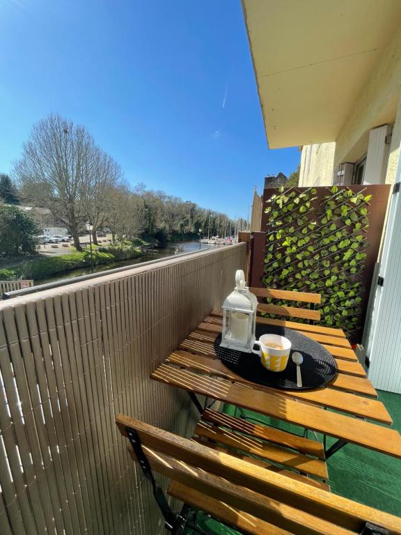 una mesa de madera con una taza de café en el balcón en Appartement avec balcon et vue sur port - wifi privé - au dessus du Restaurant le Yackams, en La Roche-Bernard