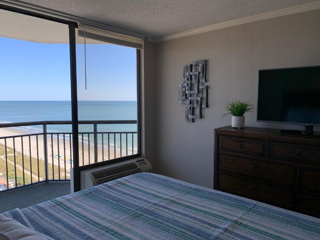 a bedroom with a bed and a television and a balcony at 1602 Coastal Soul Pet friendly in Myrtle Beach