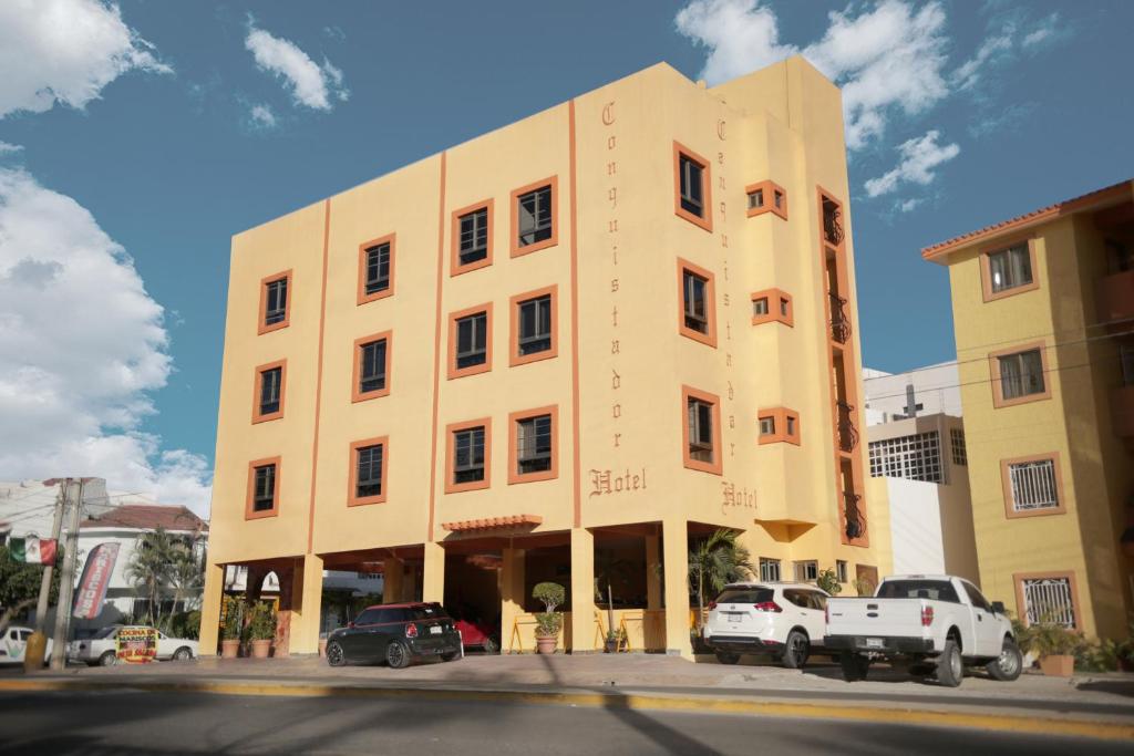 a large yellow building with cars parked in front of it at Hotel Conquistador in Mazatlán