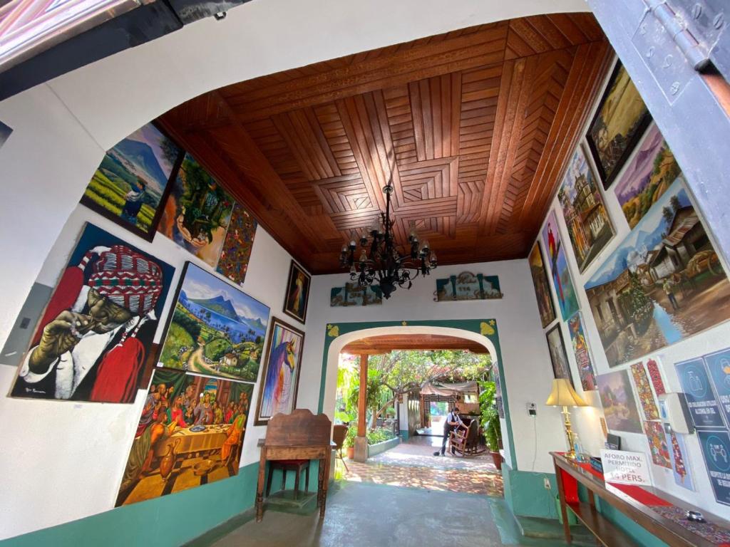 a room with paintings on the walls and an archway at Hotel Palacio Chico 1948 in Antigua Guatemala