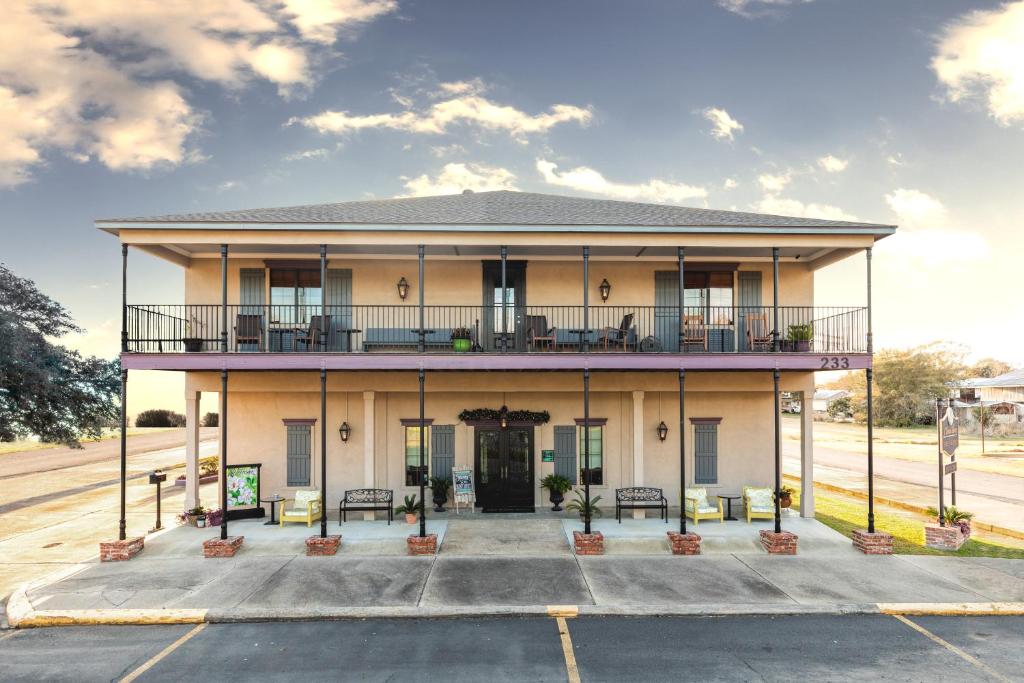 um grande edifício amarelo com um alpendre e varanda em The Bank Hotel em Lake Arthur