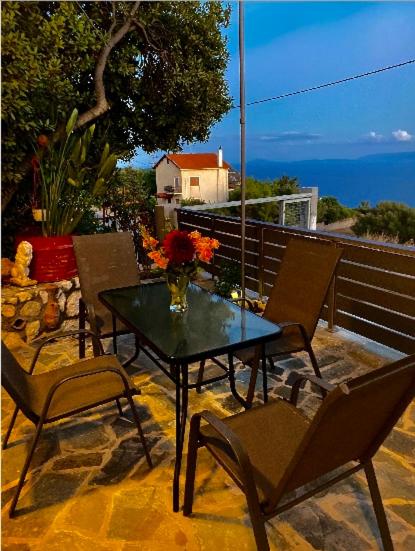 stół z krzesłami i wazon kwiatów na patio w obiekcie Dina’s house 2 w mieście Argostoli