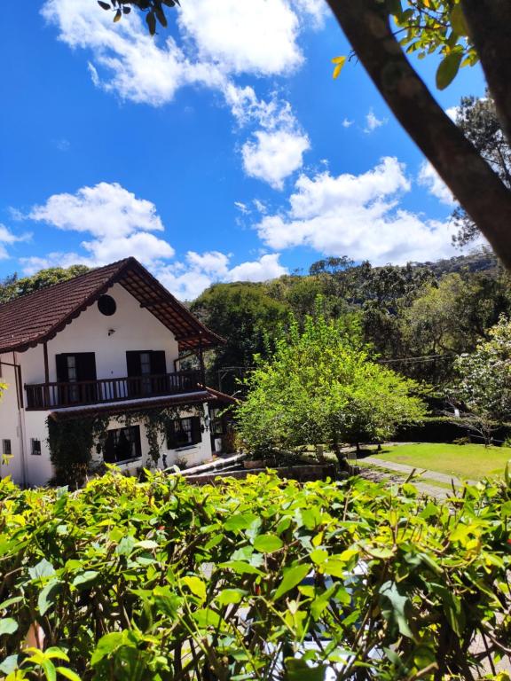 a white building with a balcony in a park at Pousada Taverna do Golf in Teresópolis