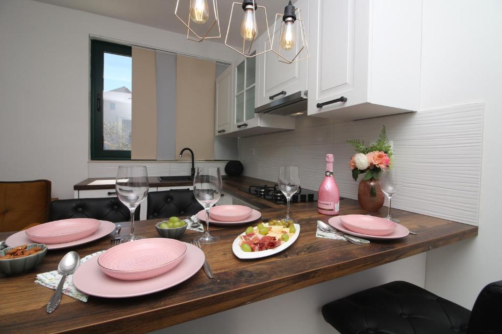 a kitchen with a table with pink plates and wine glasses at Apartments Fortunato in Zablaće
