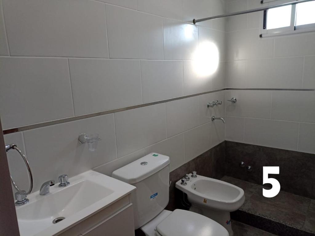 a bathroom with a white toilet and a sink at Duplex Houssay. in Libertador San Martín