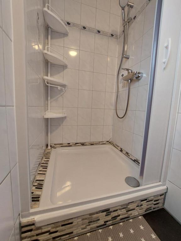 La salle de bains est pourvue d'une douche et d'une baignoire carrelée de blanc. dans l'établissement Ferienwohnung Streit, à Gohrisch