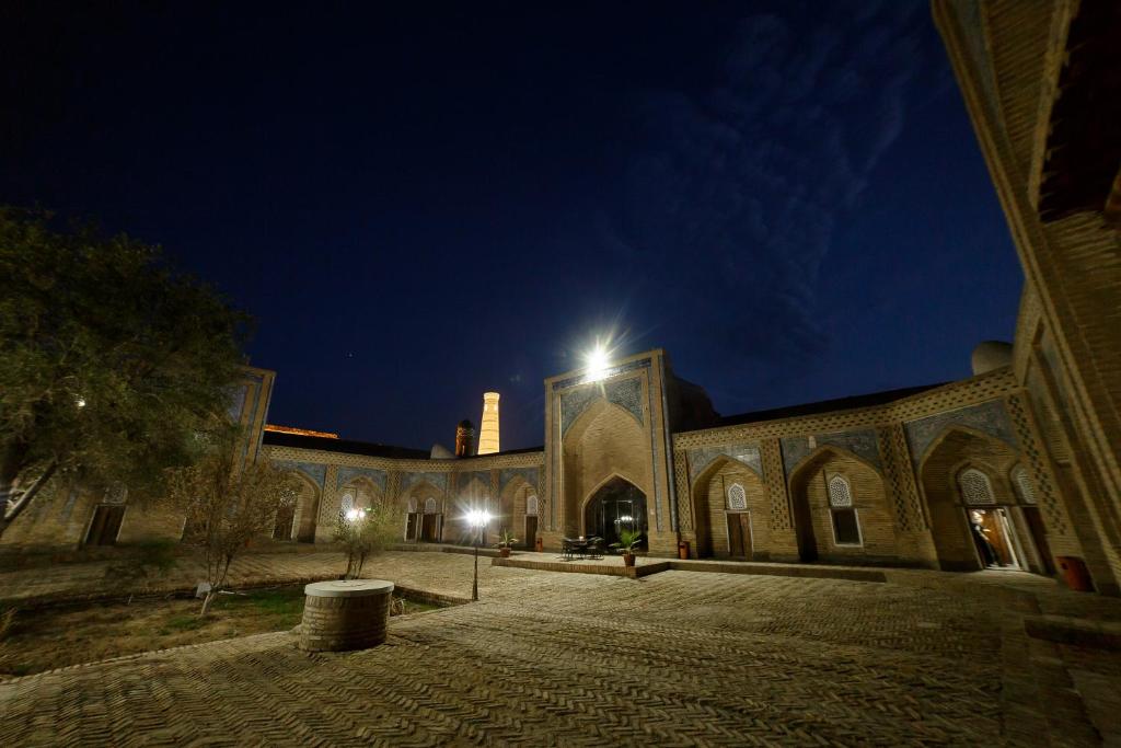 a large brick building with a tower at night at Feruzkhan Hotel - Madrassah Mohammed Rakhim Khan 1871 in Khiva