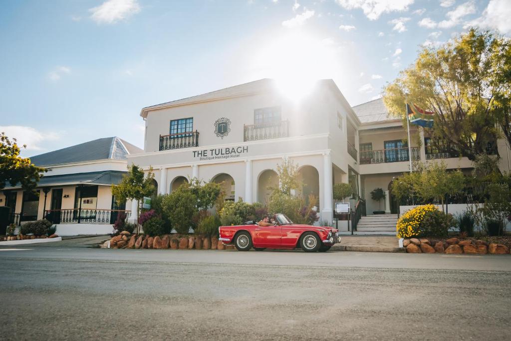 Tulbagh Boutique Heritage Hotel في تولباغ: سيارة حمراء متوقفة أمام مبنى أبيض