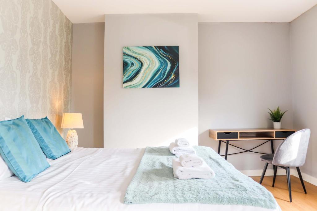 a bedroom with a bed with blue pillows and a desk at Relaxing - 3 Bed - Entire Home - Serviced Accommodation - In Heart Of Northumberland in Lynemouth