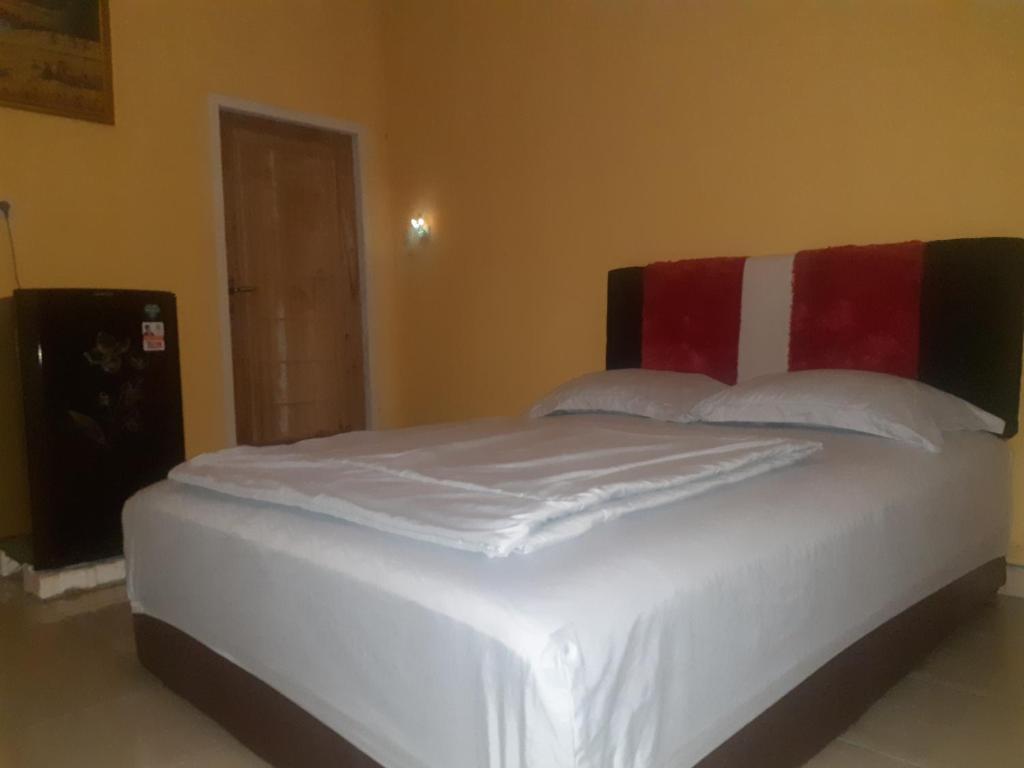um quarto com uma cama branca com almofadas vermelhas e brancas em Eltari Homestay em Tetebatu
