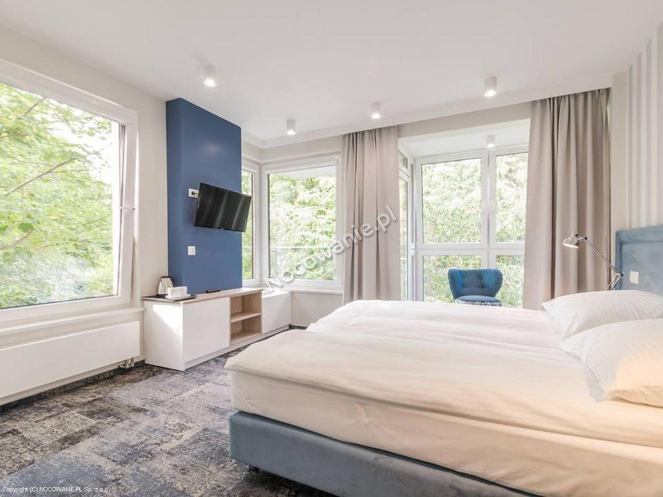 a bedroom with a large bed and a blue wall at Pensjonat Przedwiośnie in Jurata