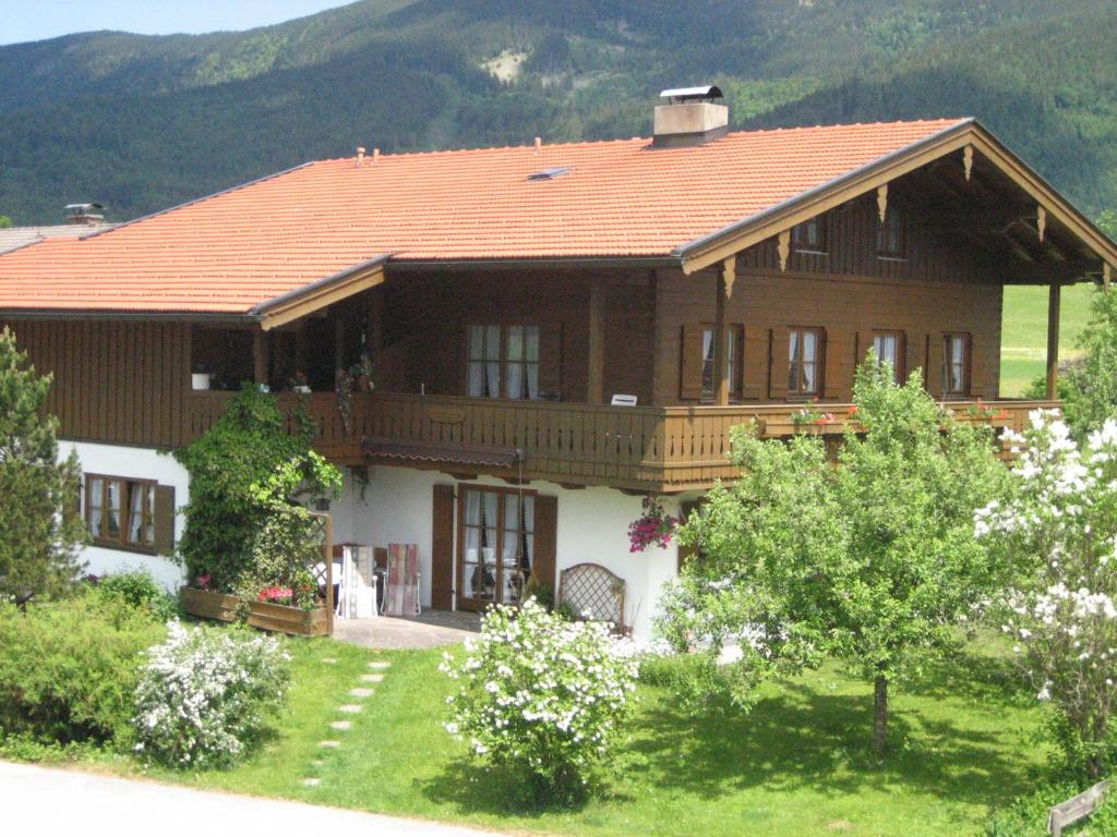 een groot houten huis met een rood dak bij Ferienwohnung Gundi Scheurl - Chiemgau Karte in Inzell