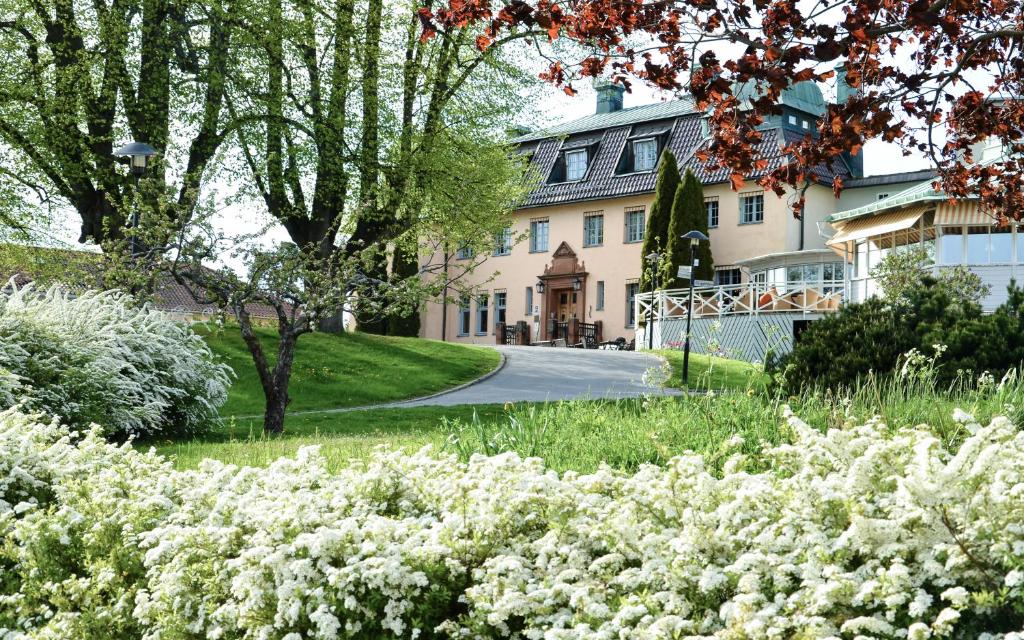 un jardin avec des fleurs blanches en face d'une maison dans l'établissement Såstaholm Hotell & Konferens, à Täby