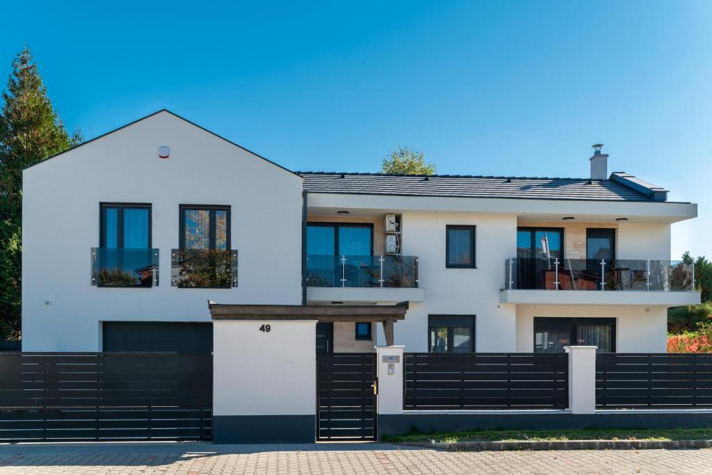 ein weißes Haus mit einem schwarzen Zaun in der Unterkunft Golden Beach Apartments Siófok in Siófok