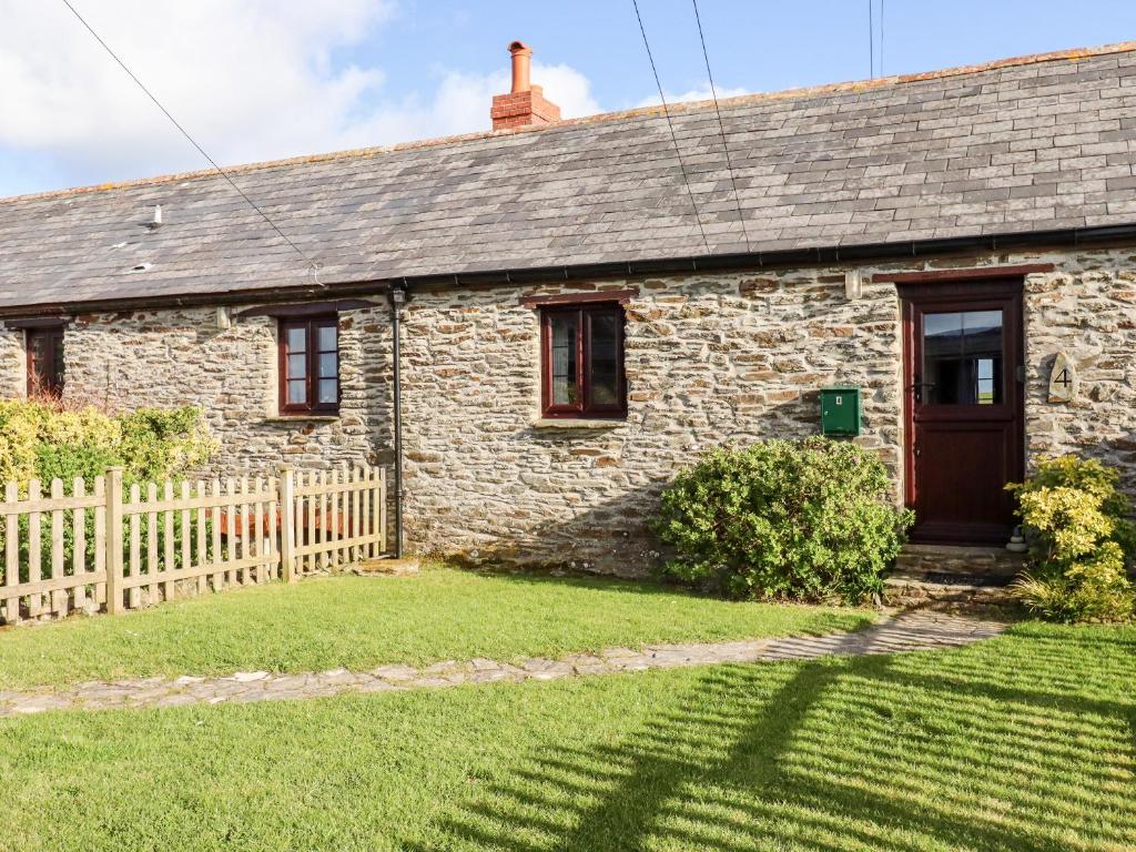 a stone house with a wooden door and a yard at 4 Mowhay Cottages in Saint Goran