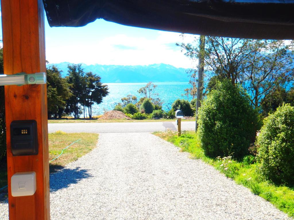 una strada sterrata con vista sull'acqua di Lakefront Fantail Cottage Lake Hawea, Wanaka a Lake Hāwea