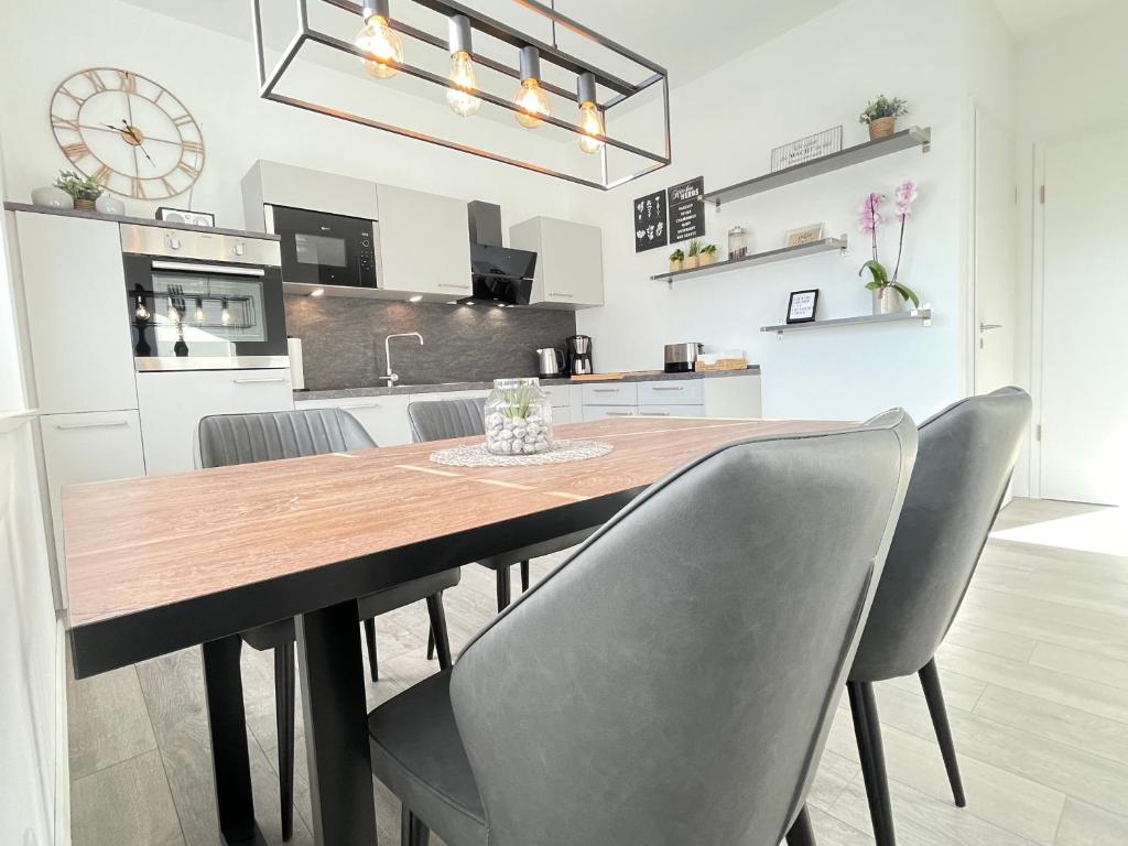 a dining room with a wooden table and chairs at Lee-Moderne Neubauwohnung in Strandnähe - Wallbox in Wremen