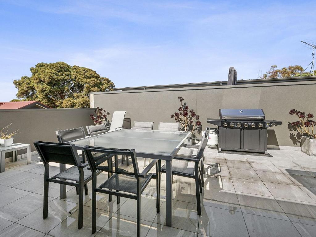 a table and chairs on a patio with a grill at Anderson Central Torquay 36 in Torquay