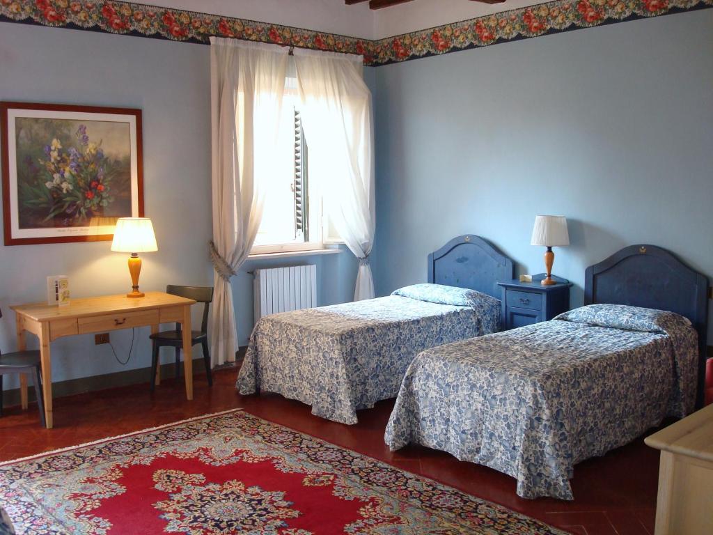 a room with two beds and a table and a window at Soggiorno Dimora Del Grifo in San Miniato