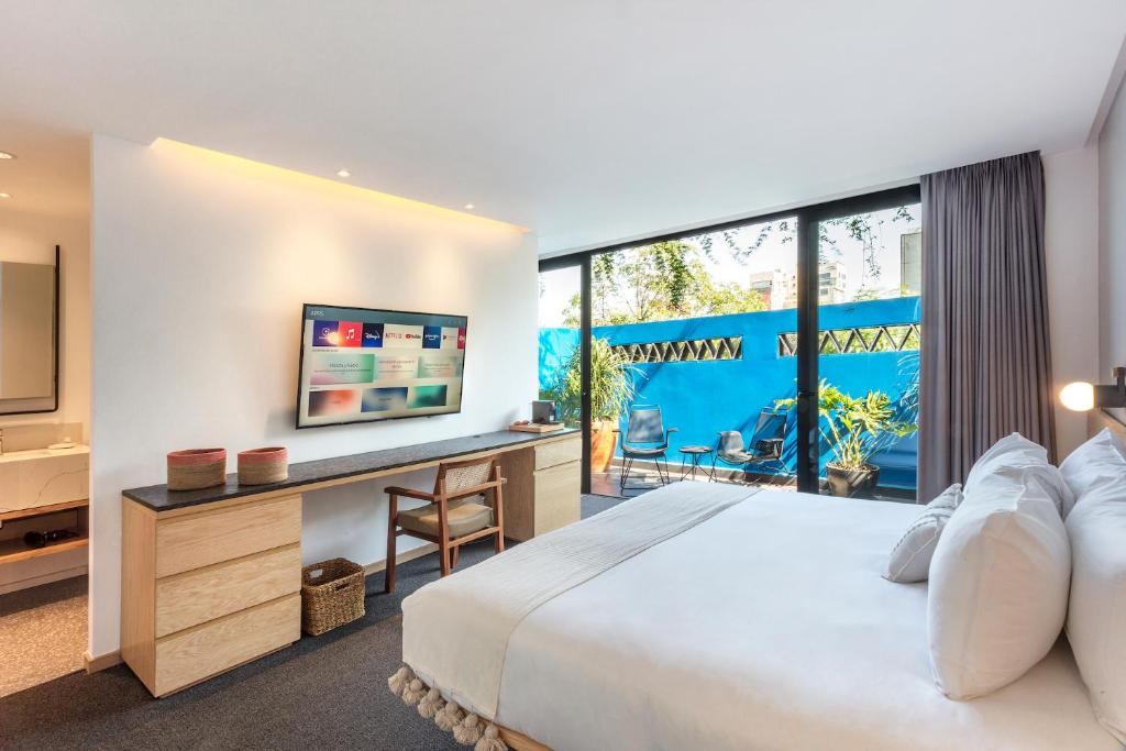 een slaapkamer met een bed en een bureau met een televisie bij V65 Mx in Mexico-Stad