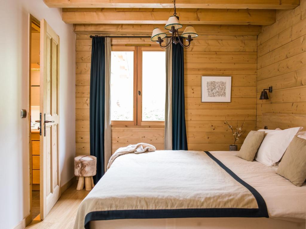 a bedroom with wooden walls and a bed with a window at Les Chalets des Liarets in Chamonix