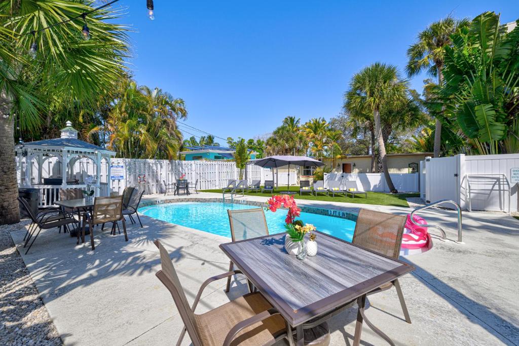 a patio with a wooden table and chairs next to a pool at The Ringling Beach House in Siesta Key