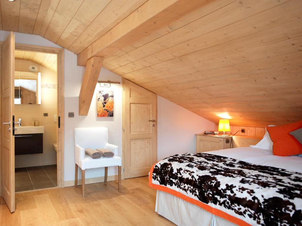 a bedroom with a bed and a white chair at Les Chalets des Liarets in Chamonix