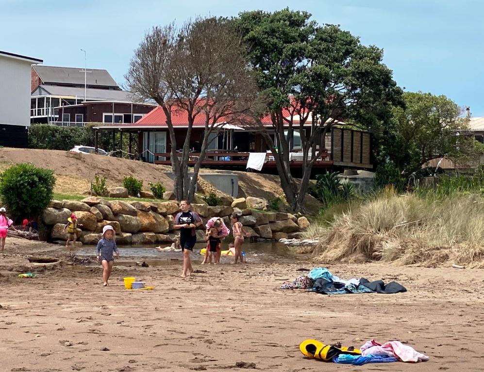 a group of people standing on a beach at Bay of Islands Beachfront - Tapeka del Mar in Russell