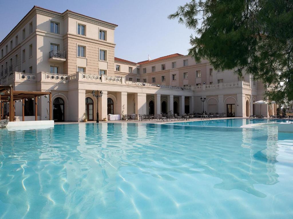 a large swimming pool in front of a building at Grecotel Larissa Imperial in Larisa