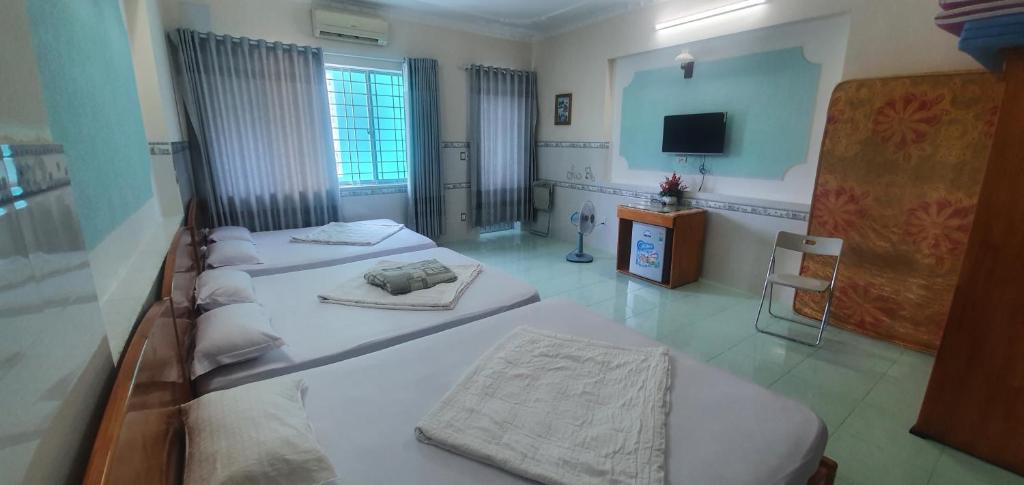 ein Schlafzimmer mit 3 Betten und einem TV. in der Unterkunft Thanh Sơn Motel in Vũng Tàu