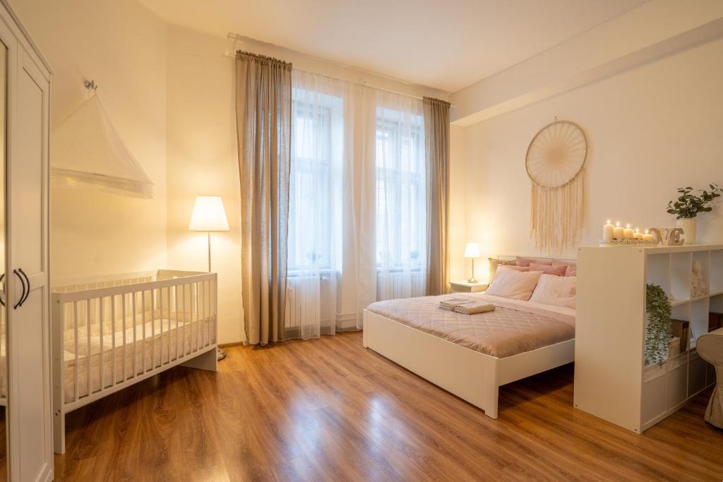 a white bedroom with a crib and a large window at FAMILY Apartment OSTRAVA in Ostrava