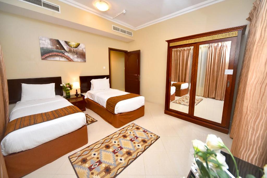 a hotel room with two beds and a mirror at Emirates Stars Hotel Apartments Sharjah in Sharjah