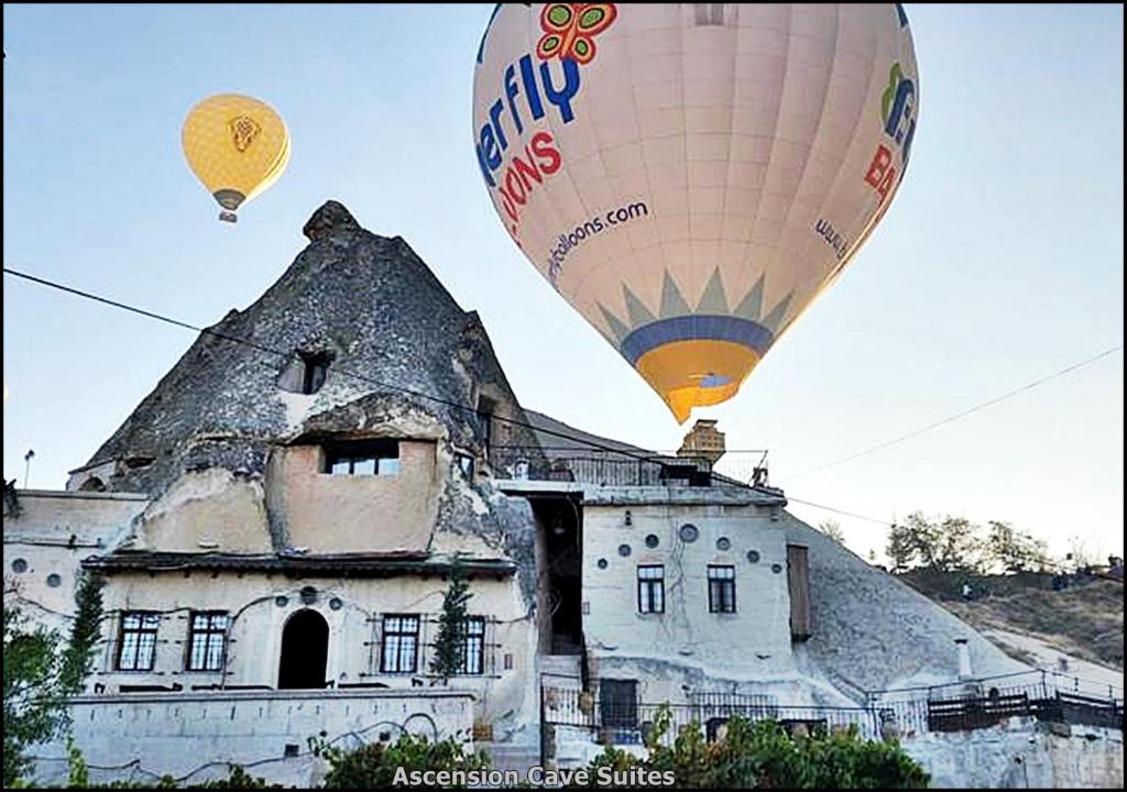 two hot air balloons flying over an old building at Ascension Cave Suites - Special Class in Goreme