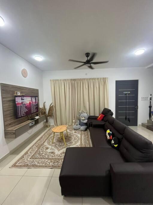 sala de estar con sofá negro y TV en Hadeerna Homestay - Double storey terrace, en Chemor