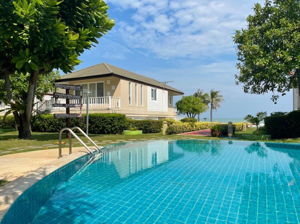 a swimming pool in front of a house at RIM Chaam By RoomQuest in Cha Am