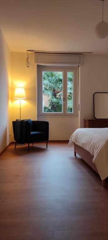 ein Schlafzimmer mit einem Bett, einem Fenster und einem Stuhl in der Unterkunft casa Dante in Riva del Garda