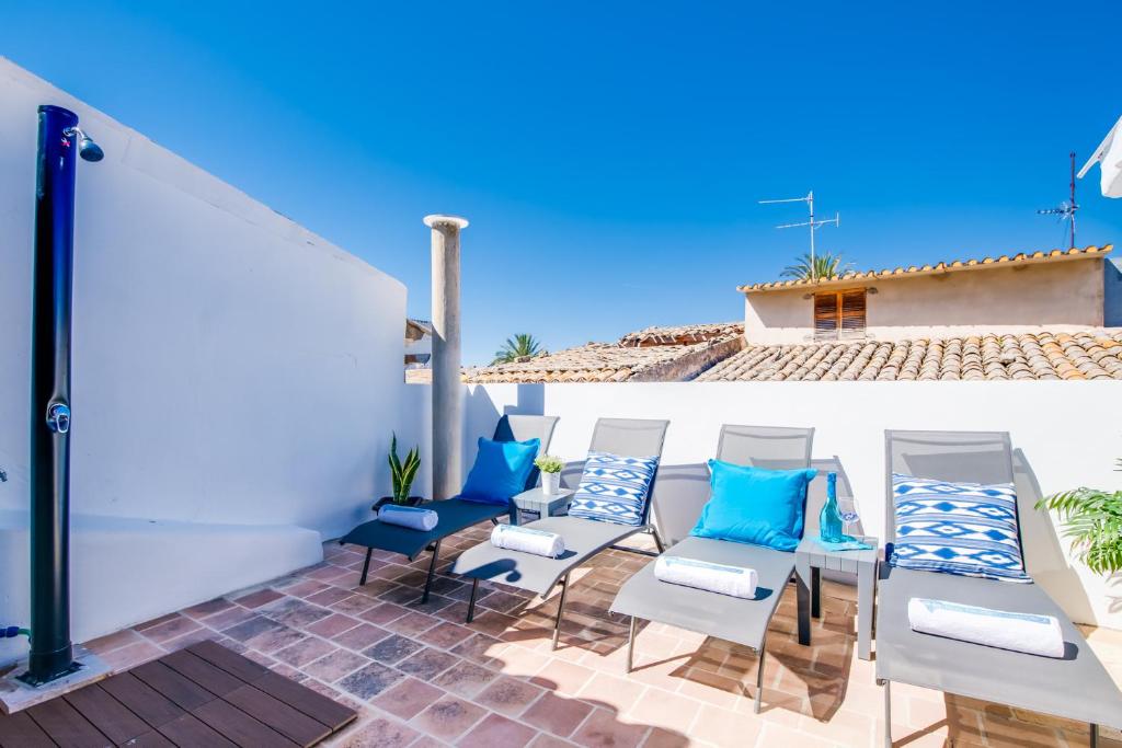 a patio with blue and white chairs and a white wall at Ca na Serrieta in Alcudia