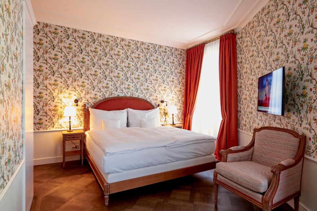 a bedroom with a bed and a chair at Château Gütsch in Luzern