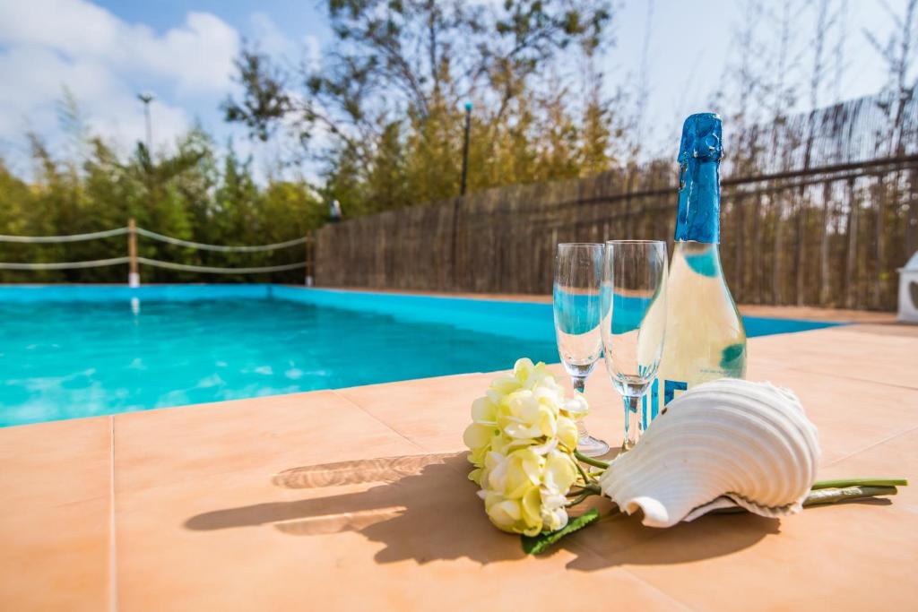 Una botella de champán y dos copas en una mesa cerca de una piscina. en Ideal Property Mallorca - Can Caragol Font de Sa Cala, en Capdepera