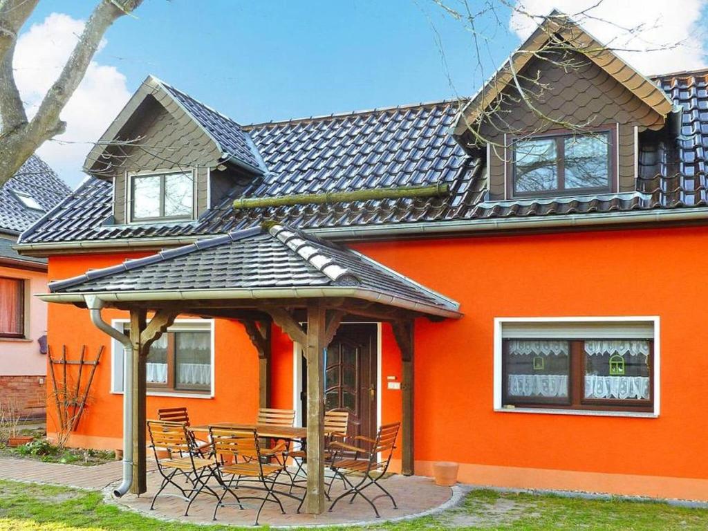 une maison orange avec des chaises et un kiosque dans l'établissement Holiday house to the stork's nest, Storkow, à Storkow