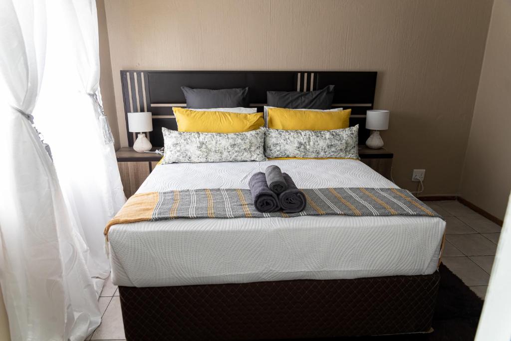 a bedroom with a large bed with yellow pillows at The Hide in Randburg in Johannesburg