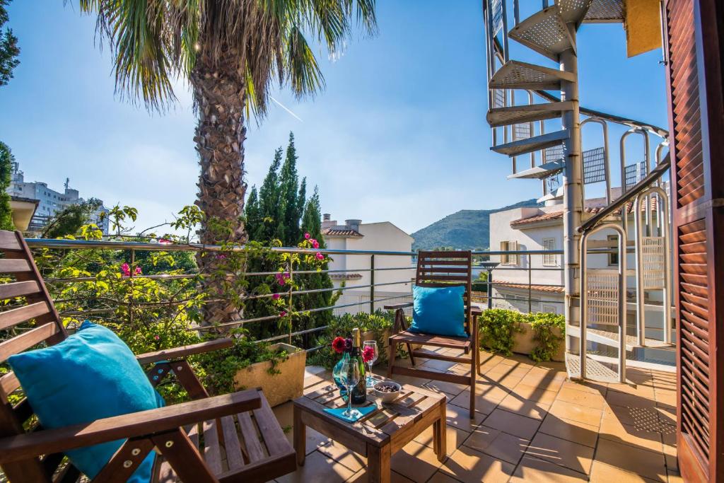 einen Balkon mit Stühlen, einem Tisch und einer Palme in der Unterkunft Ideal Property Mallorca - Luca in Alcúdia