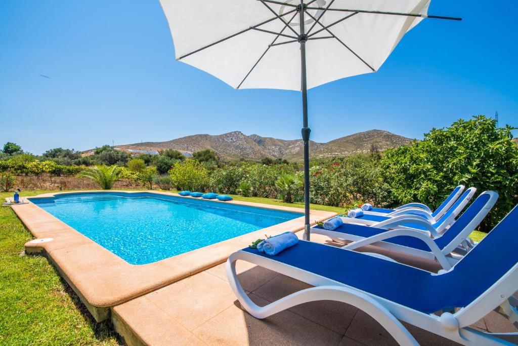 una piscina con sillas, una sombrilla y una piscina en Ideal Property Mallorca - Mamici en Capdepera