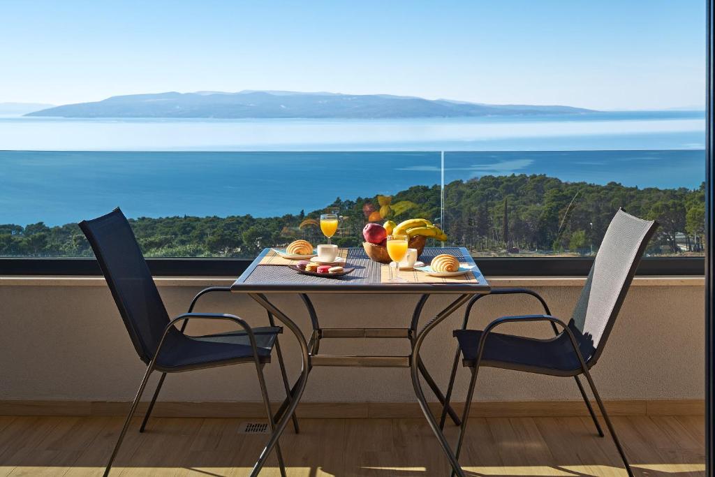 einen Esstisch mit 2 Stühlen und Meerblick in der Unterkunft Sun Spalato Residence in Makarska