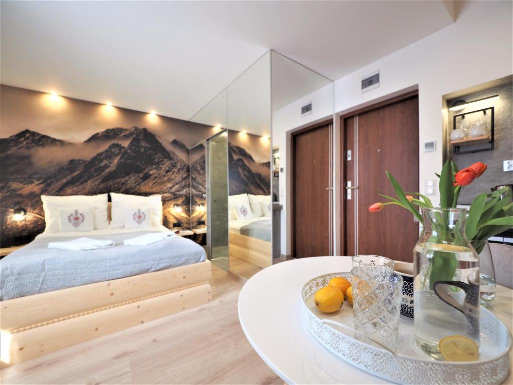- une chambre avec un lit et une table avec un vase dans l'établissement Gawra Apartament Studio, à Zakopane
