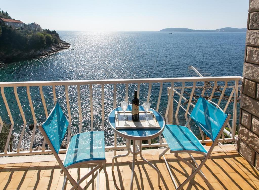 una mesa y sillas en un balcón con vistas al agua en Apartments Neve, en Dubrovnik