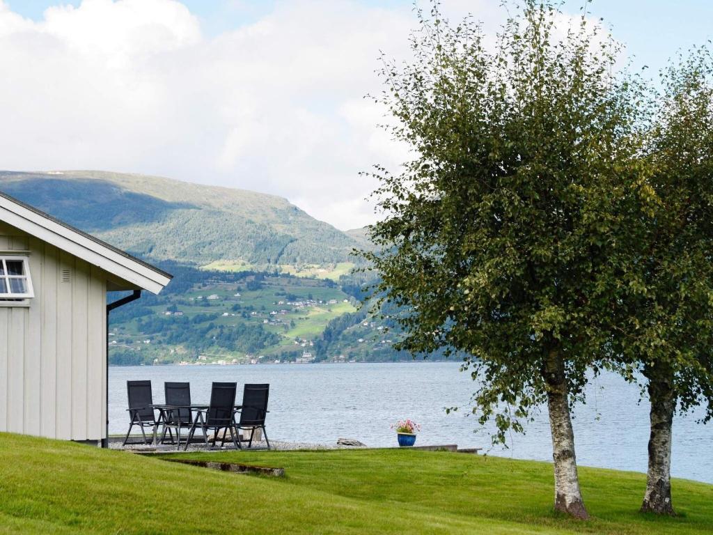 UtvikにあるHoliday home Utvik IVの湖畔の木と椅子のある家