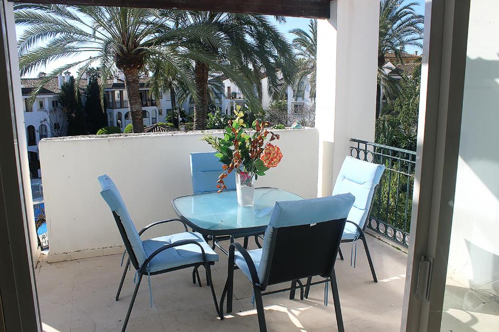 a blue table and chairs on a balcony with palm trees at Hacienda Beach in Estepona