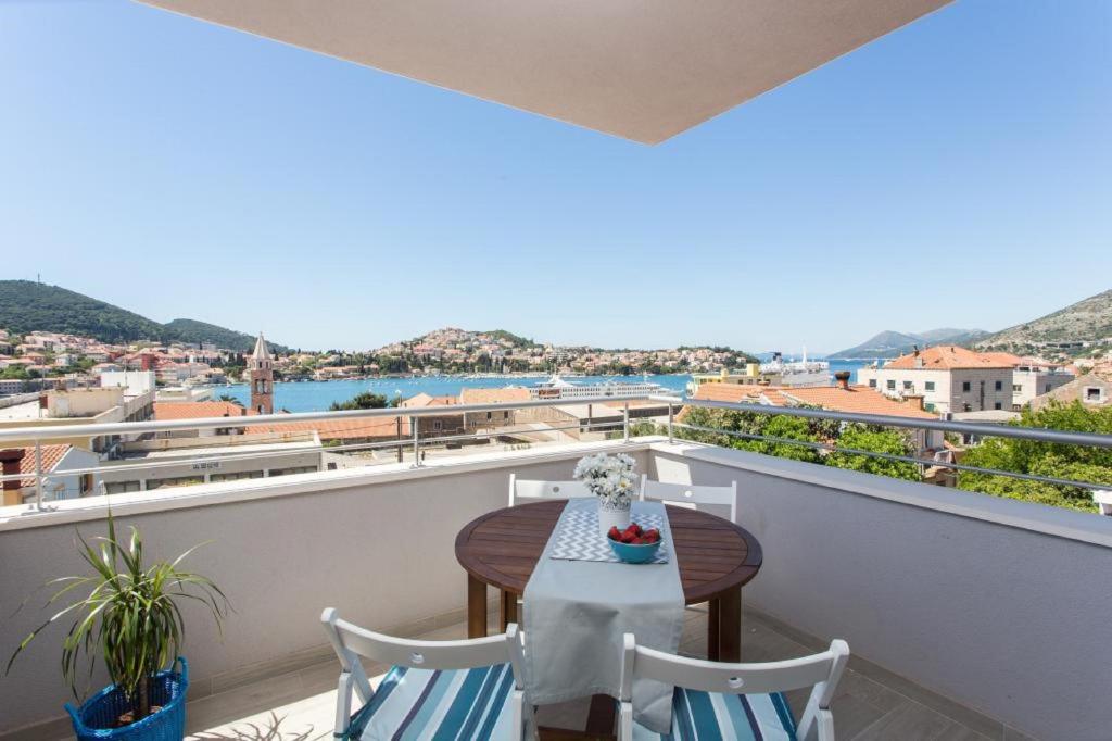 einen Balkon mit einem Tisch und Stühlen sowie Blick auf das Wasser in der Unterkunft Apartments Villa Karmen in Dubrovnik