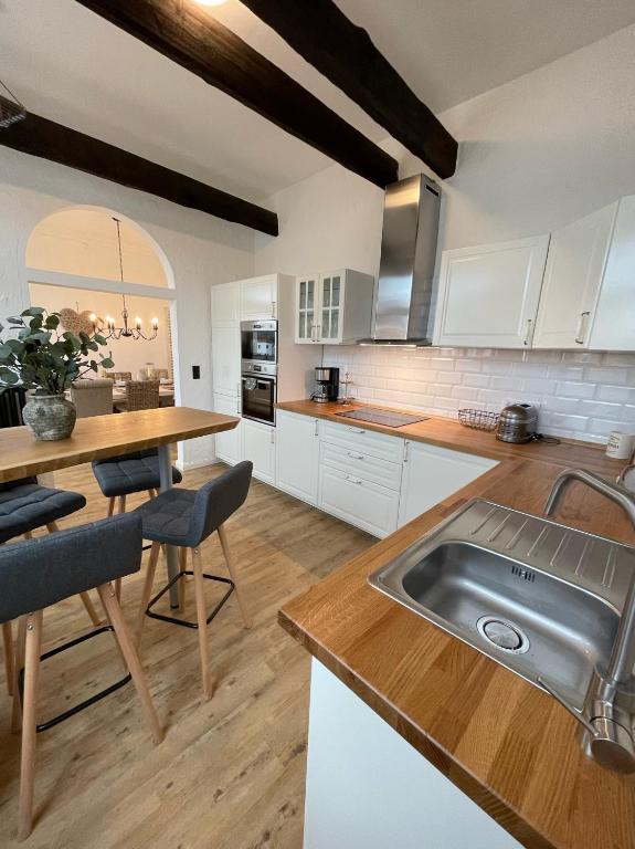 a kitchen with white cabinets and a sink and a table at Ferienwohnung Brückenkopf OG in Hameln